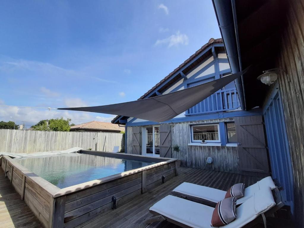 a swimming pool with a hammock and a house at Maison Landaise pour 12 personnes proche océan, piscine, WIFI inclus - FR-1-50-165 in Bias