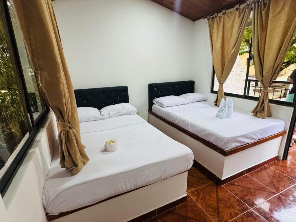 two beds sitting in a room with windows at Hotel la Isabella SM in Villeta