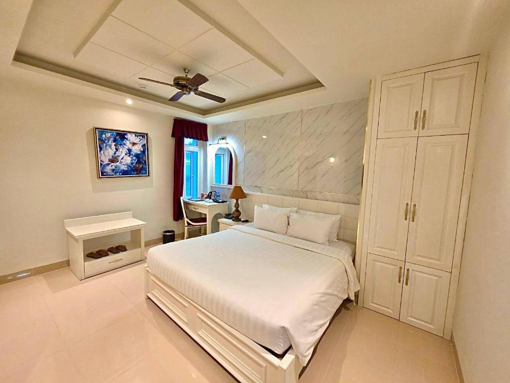 a bedroom with a white bed and a desk at Tulip Hotel 3 in Da Lat