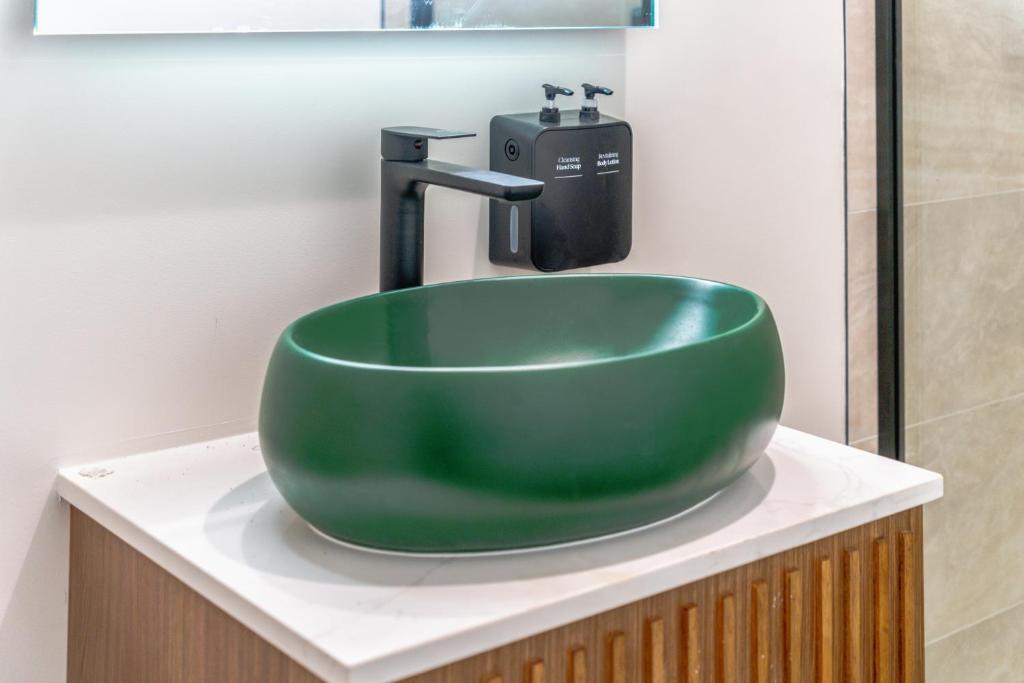ロサンゼルスにあるLYFE INN & SUITES by AGA- North Hollywood Universal Studiosのバスルームカウンターの上に緑のシンクが備わります。