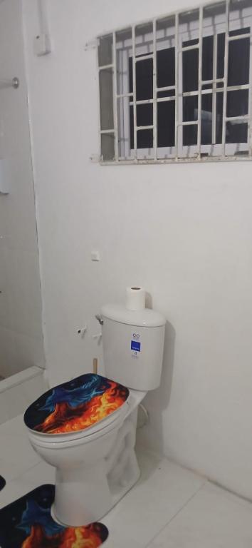bagno bianco con servizi igienici e sedia colorata. di Holiday Rooms in Port Morant St Thomas Jamaica a Port Morant