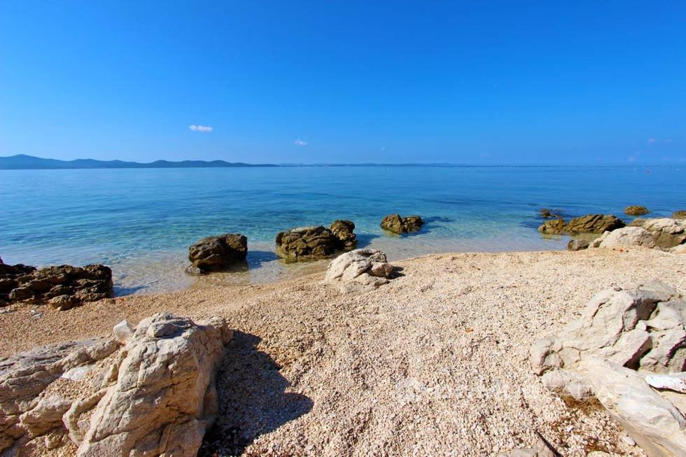 une plage de sable avec des rochers et l'océan dans l'établissement Apartment Kristy, à Zadar