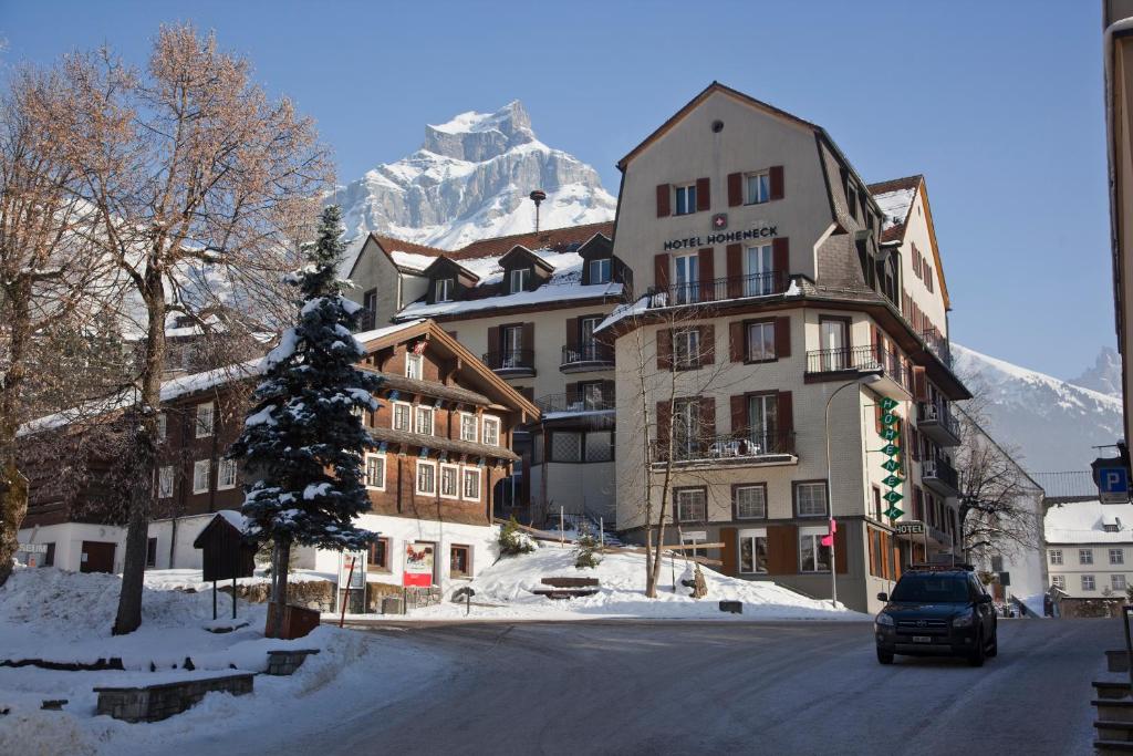 a building on a street with a snow covered mountain at Hotel Hoheneck- self check-in in Engelberg