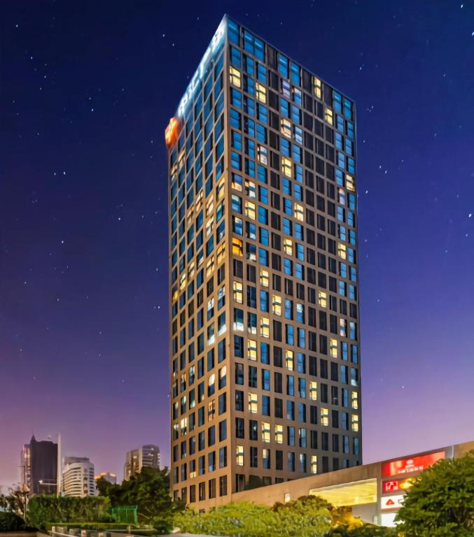 广州Poly Pivot International Aparthotel Guangzhou East Railway Branch - Free Shuttle Bus to Canton Fair Complex During Canton Fair Period的一座高大的建筑,晚上有很多窗户
