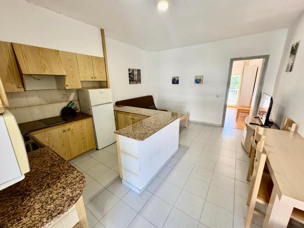 Una cocina con gabinetes de madera y encimera. en Vela el Vent 1, en Sant Carles de la Ràpita