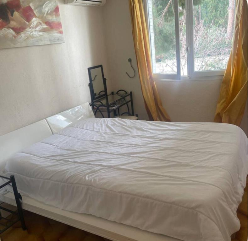 un lit blanc dans une chambre avec une fenêtre dans l'établissement 3 pièces Cannes 300m de la plage, à Cannes