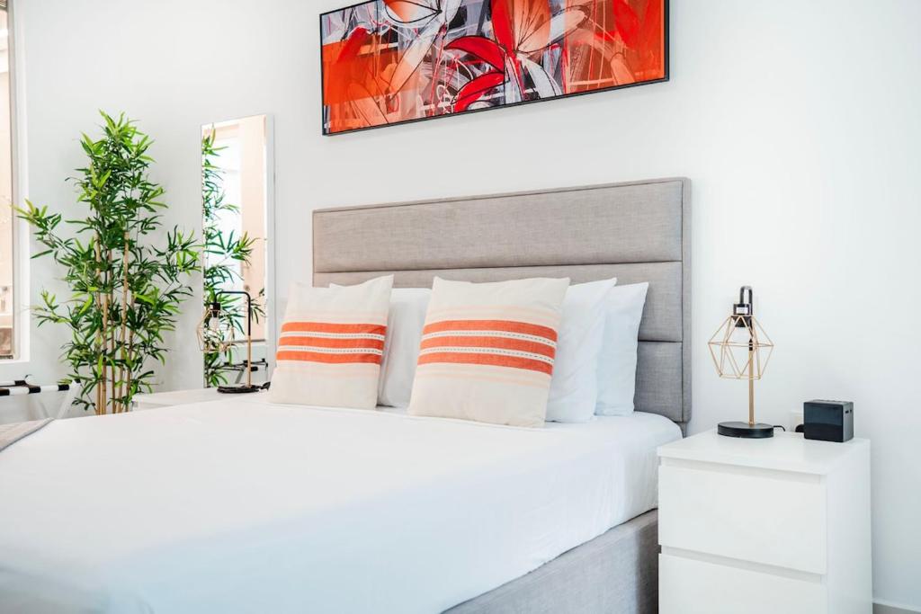 ein Schlafzimmer mit einem weißen Bett mit orangefarbenen und weißen Kissen in der Unterkunft Beautiful Palm Studio with a Wow View in Dubai