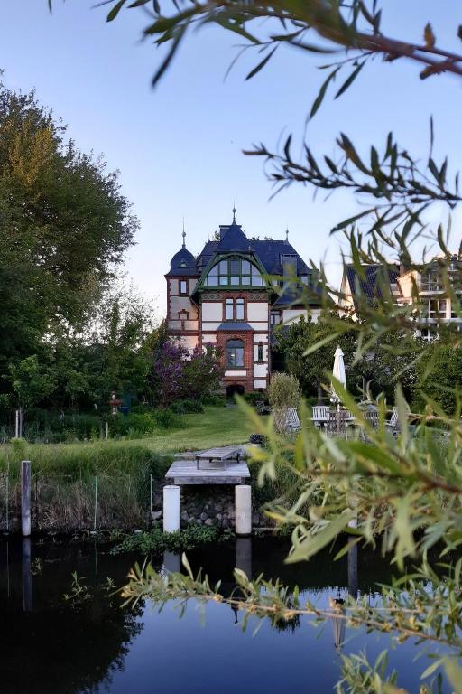 a large house on a hill next to a body of water at Villa Daries - Ferienwohnung mit eigenem Müritzstrand in Waren