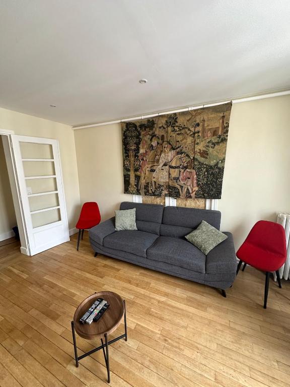 un salon avec un canapé et des chaises rouges dans l'établissement Appartement place Nevers, à Charleville-Mézières