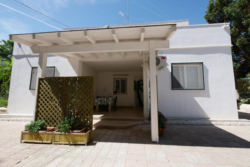 a white house with a pergola and a patio at Residence Oasis Punta Prosciutto in Punta Prosciutto