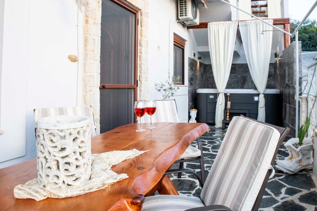 a wooden table with two glasses of wine at Cleopatra deluxe with jacuzzi apart in Kamilari with panoramic view in Kamilari