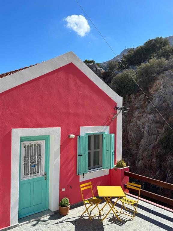 a red and white building with two chairs and a window at Casa Di Rosse in Symi