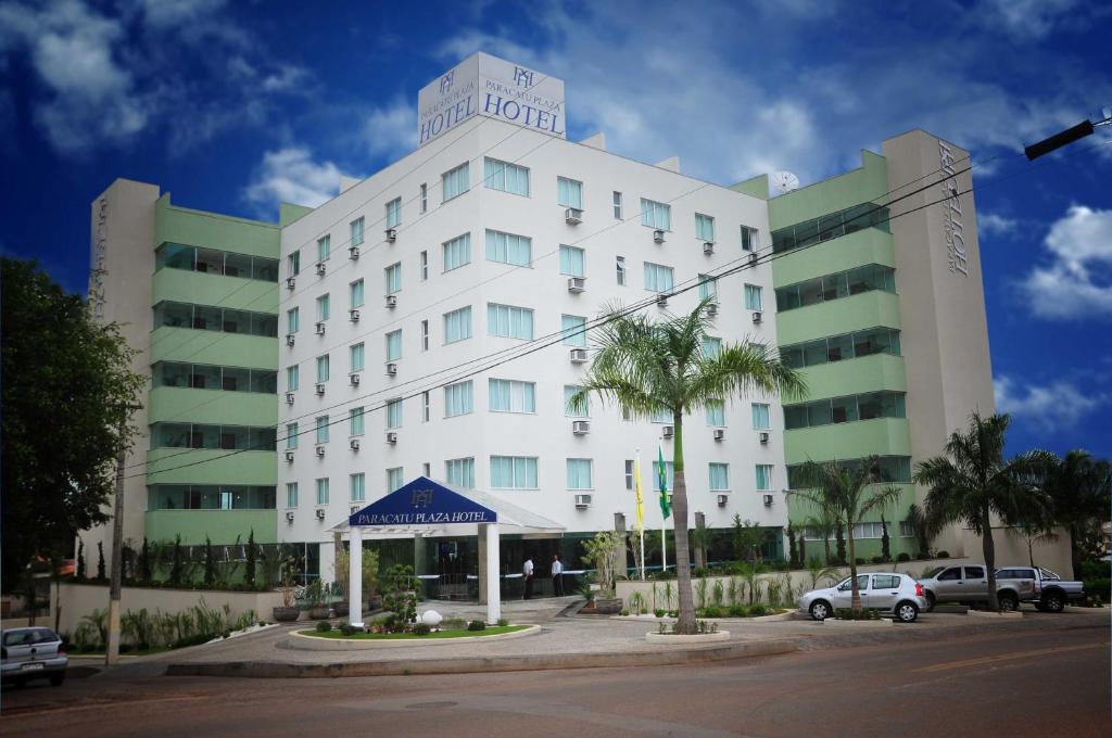 a large white building with a palm tree in front of it at Paracatu Plaza Hotel in Paracatu