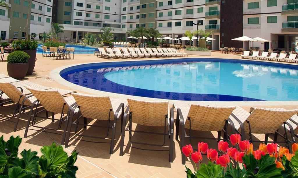 una piscina con sillas y flores frente a un hotel en Apartamentos Boulevard, en Caldas Novas