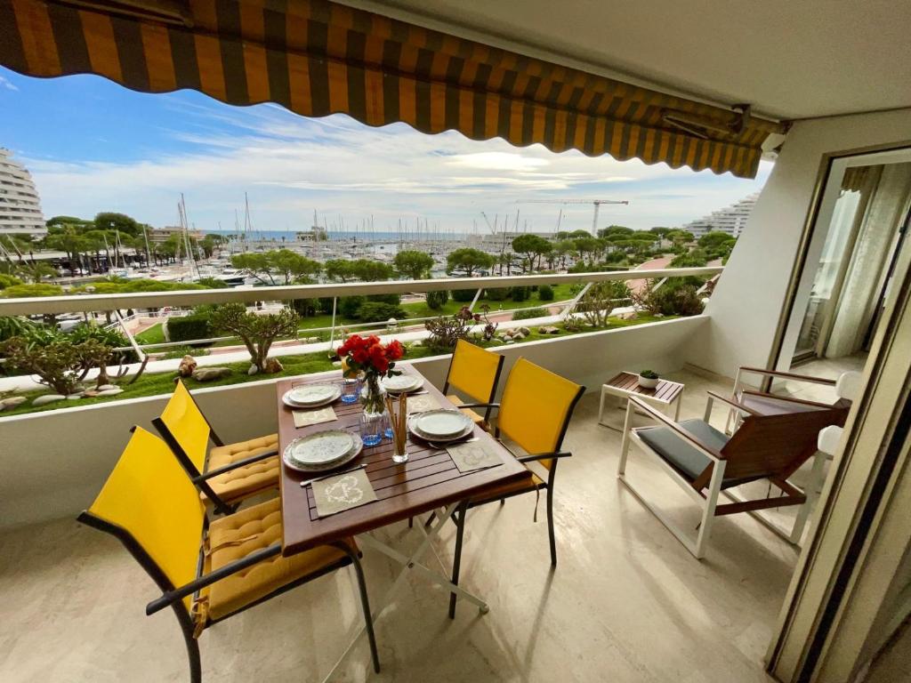 une salle à manger avec une table et des chaises et un balcon dans l'établissement Bel appartement Vue sur la Marina Classé 3 étoiles, à Villeneuve-Loubet