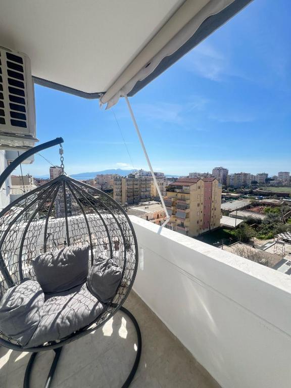Una silla en un balcón con vista a una ciudad. en Andria Apartment, en Sarandë