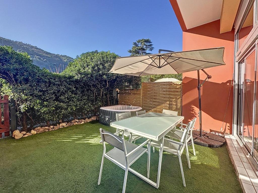 une table et des chaises avec un parasol sur une pelouse dans l'établissement Élégance et Détente - Parking - Jardin & SPA, à Menton