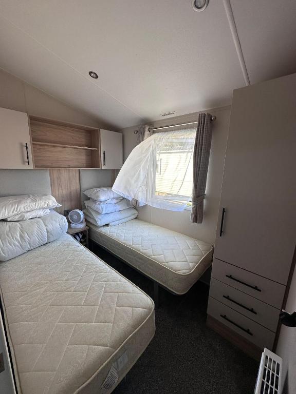 une petite chambre avec deux lits et une fenêtre dans l'établissement Caravan Selsey, à Selsey