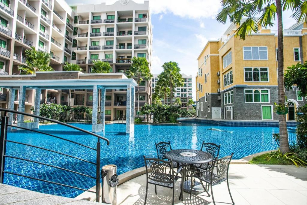 a swimming pool with a table and chairs next to a building at Arcadia阿卡迪亚二期 in Pattaya South