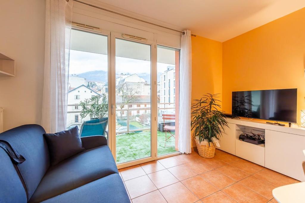 un salon avec un canapé et une grande fenêtre dans l'établissement L'Alaix vivez le cœur de ville, à Aix-les-Bains