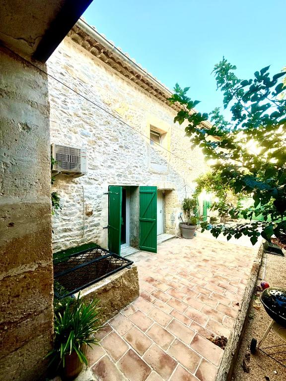 - un bâtiment en briques avec des portes vertes et une terrasse dans l'établissement Maison Provençale, Piscine, Soleil, Barbecue et Pétanque, à Saint-Gervasy