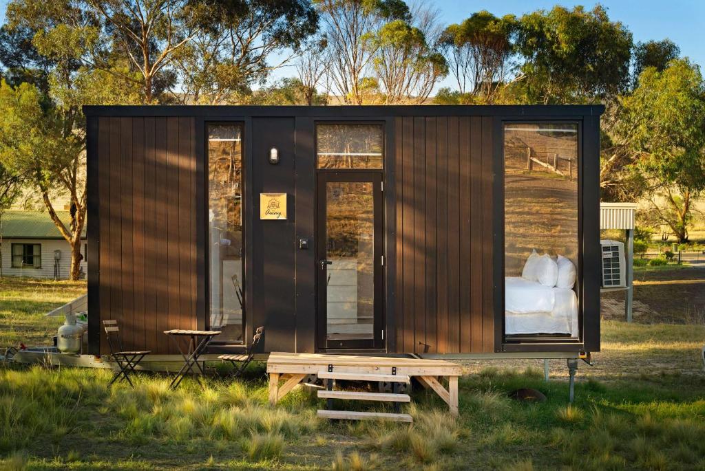 a tiny house in a field with a bench at Rowsley Valley Tiny House 2 by Tiny Away in Ingliston