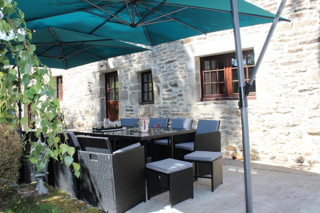 une table et des chaises sous un parapluie bleu dans l'établissement La Longère de Quily en Brocéliande 12 couchages bain nordique, à Villeder