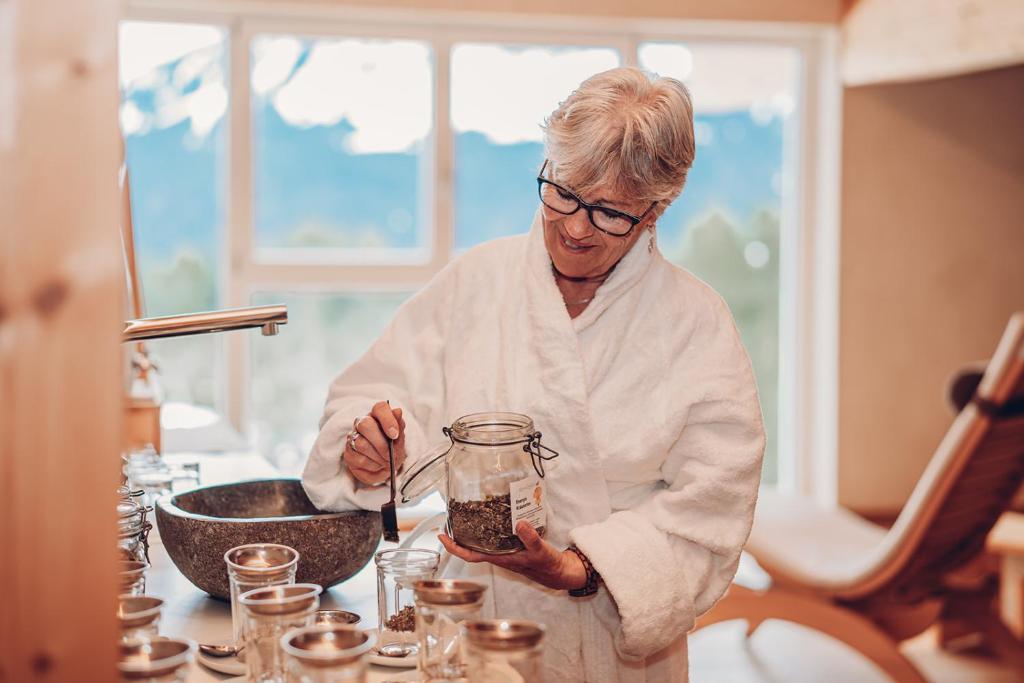 a woman standing in a kitchen preparing food in a jar at Alpengasthof Hörnlepass in Riezlern