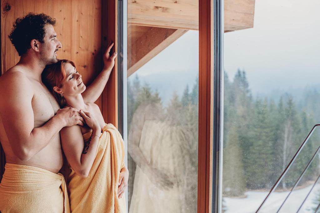 a man and a woman standing next to a window at Alpengasthof Hörnlepass in Riezlern