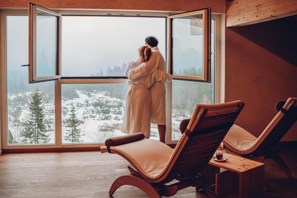 a woman standing on a window looking out at the snow at Alpengasthof Hörnlepass in Riezlern