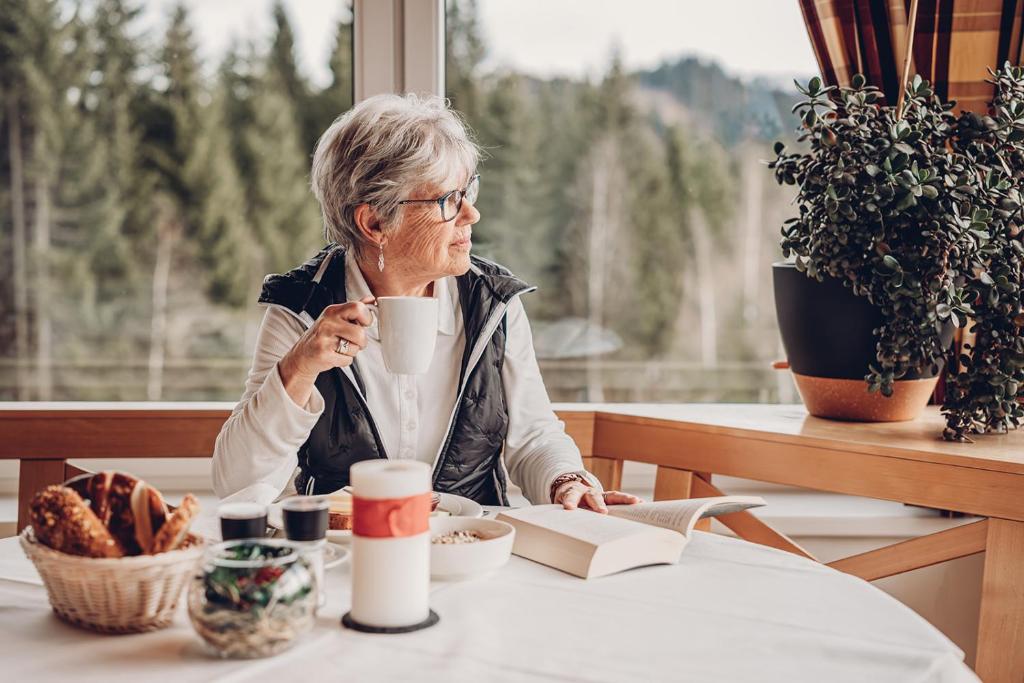 an older woman sitting at a table eating food at Alpengasthof Hörnlepass in Riezlern