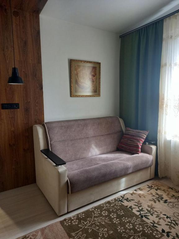 a couch sitting in a living room next to a window at Двухкомнатные апартаменты in Odesa