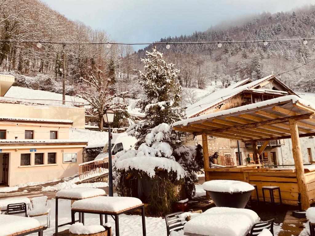 un cortile coperto da neve con sedie e una casa di Auberge le bois du cornet a La Forclaz