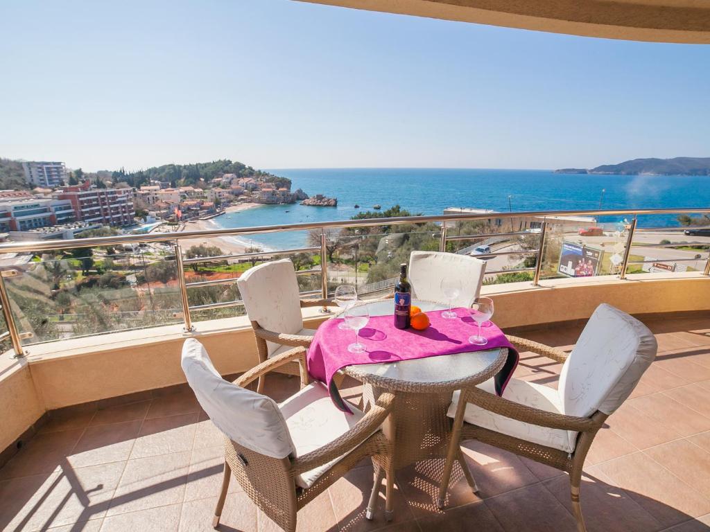 a table and chairs on a balcony with a view of the ocean at Apartments Raymond in Sveti Stefan