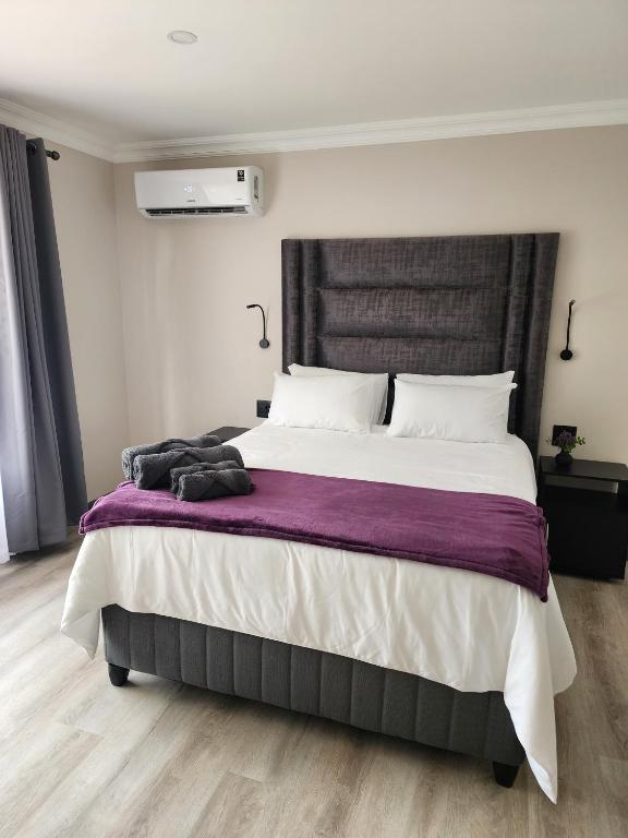 a bedroom with a large bed with purple blanket at Lavender Lofts in Centurion