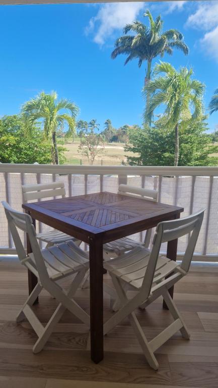 un tavolo in legno e 2 sedie su una terrazza con palme di Chez Michèle a Saint-François