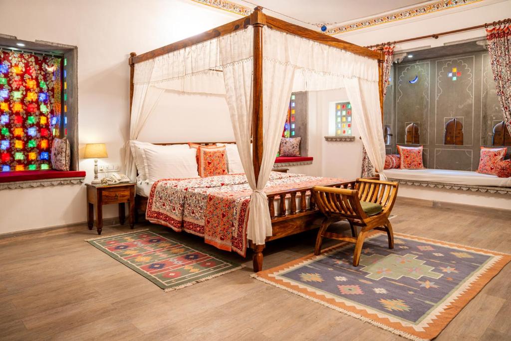 een slaapkamer met een hemelbed en een stoel bij Udaigarh - Udaipur in Udaipur