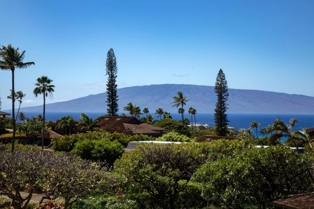 a garden with palm trees and the ocean in the background at KBM Resorts FREE CAR Kaanapali Plantation Villa 3-Bedroom 2-story Condo with Beautiful furnishings KPL-41 in Kaanapali