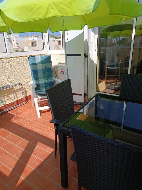 un patio avec une table, des chaises et un parasol dans l'établissement Le cocon méditerranéen, au Barcarès