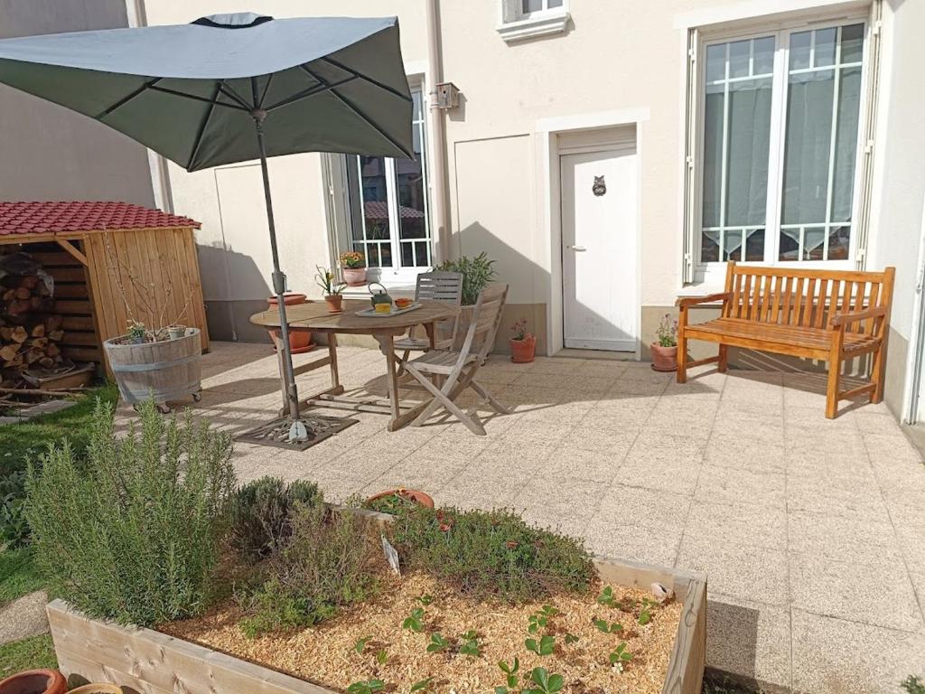 une terrasse avec un parasol, une table et un banc dans l'établissement Chambre d'hôte au Mans pour 24H Autos Motos ou autre évènement, au Mans
