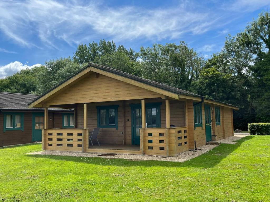 ein kleines Holzhaus mit einem Rasenhof in der Unterkunft Pochard Lodge Lakeside Fishing Parking Pass The Keys in South Cerney