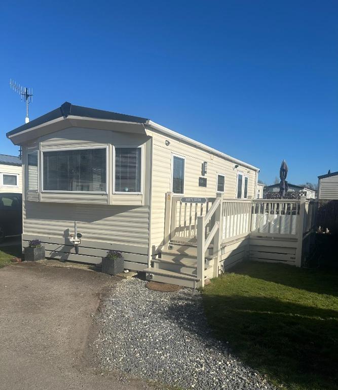 a white trailer with a porch and a fence at Happy Hilda in Selsey