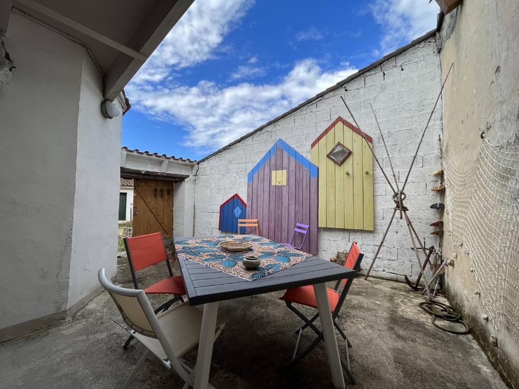 a table and chairs with a painting on a wall at Mais 4 pièces Oléron 6 couchages SAINT GEORGES D'OLERON SGO000-607 in Saint-Georges-dʼOléron
