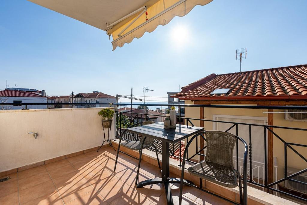 a balcony with a table and chairs on a roof at Jella's sunny apartment in Nea Skioni