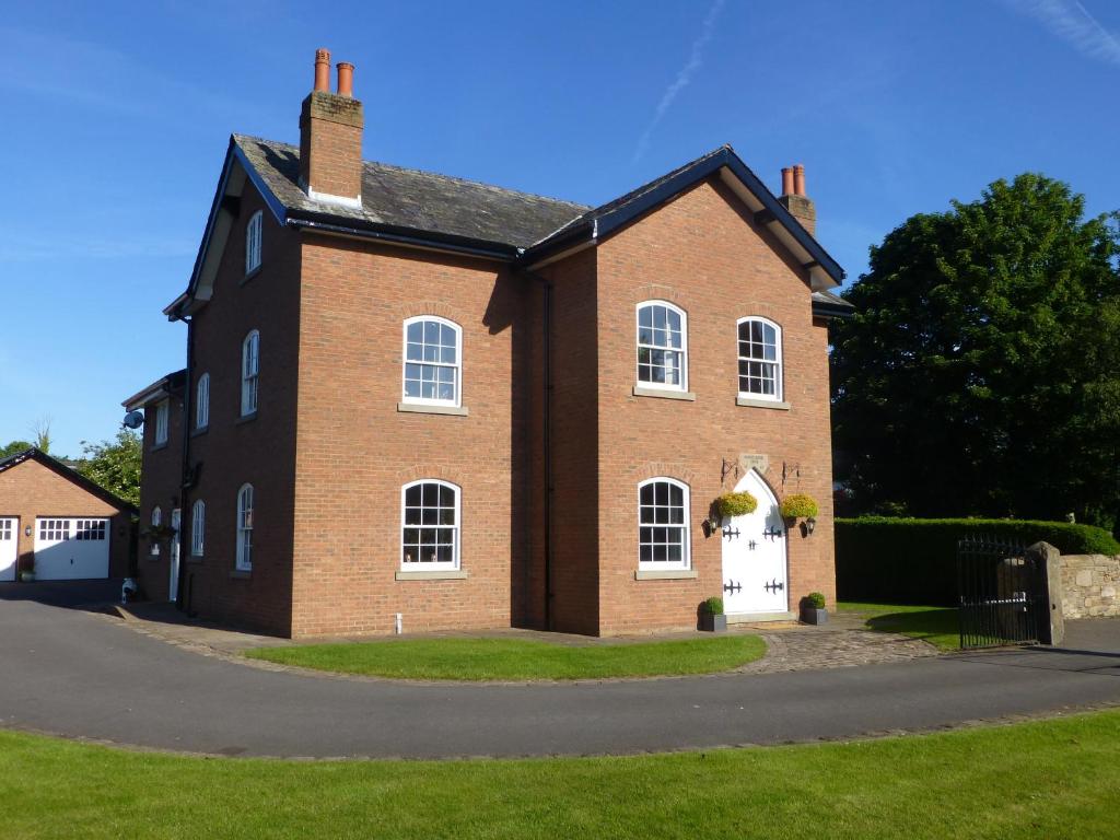 um grande edifício de tijolos vermelhos com uma porta branca em Manor House Farm em Rufford