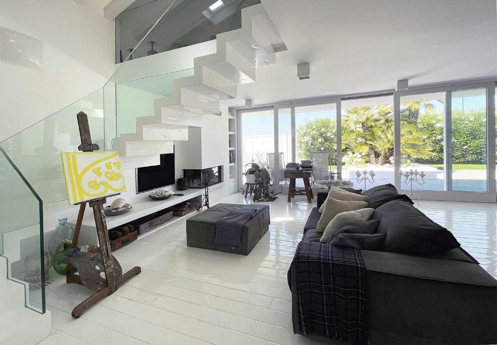 a living room with a couch and a staircase at Villa Rosa del mare - Villa fronte mare di design con camino e giardino privato in Marzocca di Senigallia