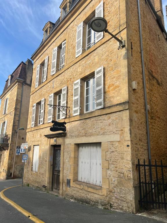 Un edificio de ladrillo con una puerta blanca en una calle. en Sarlat en Couleurs, en Sarlat-la-Canéda