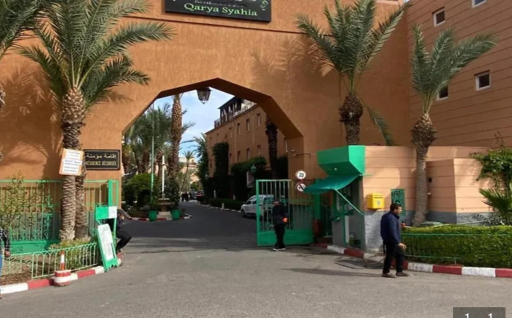 a man standing in front of a building with palm trees at Bienvenus dans un beau nouveau Riad Tout Entier in Marrakech