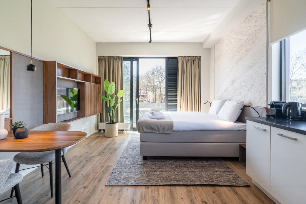 a bedroom with a bed and a table and a kitchen at Utrecht City Apartments - Huizingalaan in Utrecht