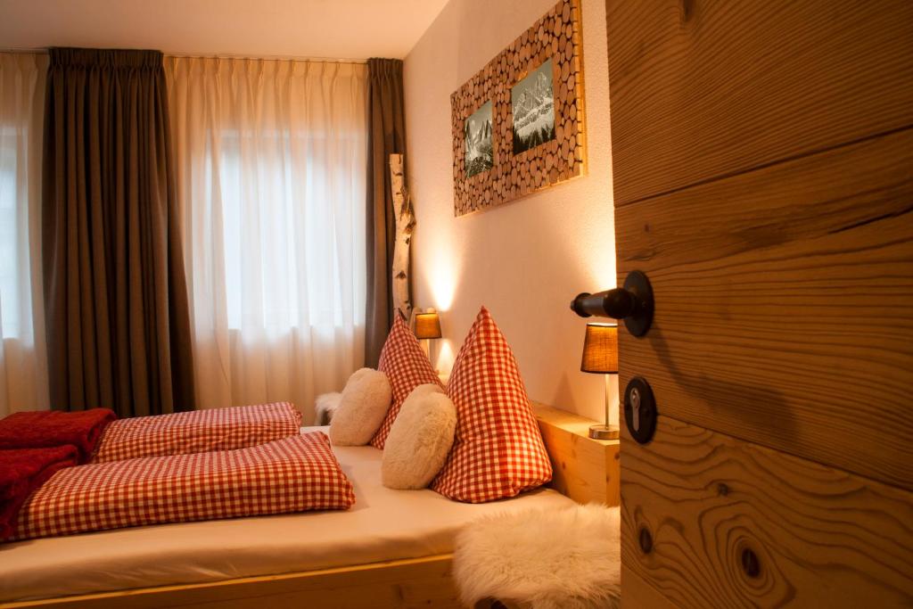 a bedroom with a bed with pillows and a window at Preindlerhof Farmhouse in Santa Maddalena in Casies